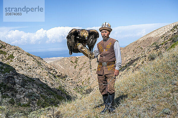 Traditional Kyrgyz eagle hunter with eagle in the mountains  hunting  near Bokonbayevo  Issyk Kul region  Kyrgyzstan  Asia