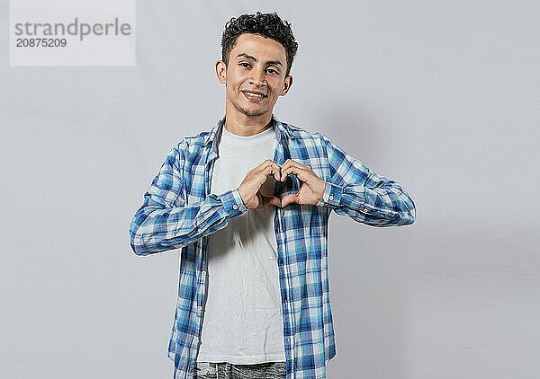 Smiling guy making heart shape with hands isolated. Happy man making heart shape with hands isolated. Person putting hands together in a heart shape