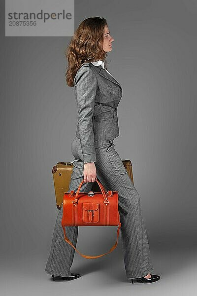 A businesswoman with a bag and a suitcase. On a gray background