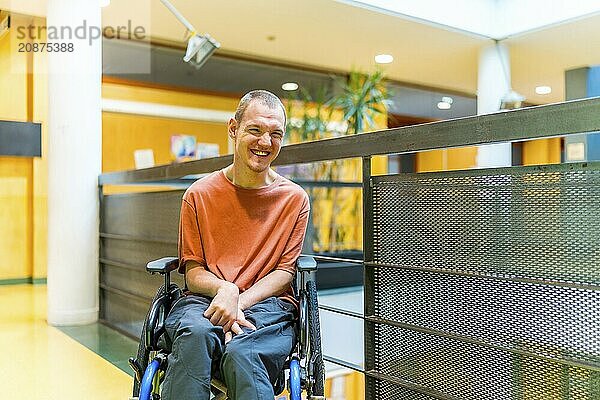 Happy man with cerebral palsy in a modern coworking smiling at camera in the corridor