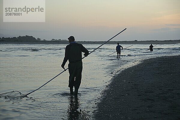 HOKITIKA  NEW ZEALAND  OCTOBER 24  2019: A man uses a scoop net at sunset for catching whitebait at the Hokitika River on the West Coast of the South Island