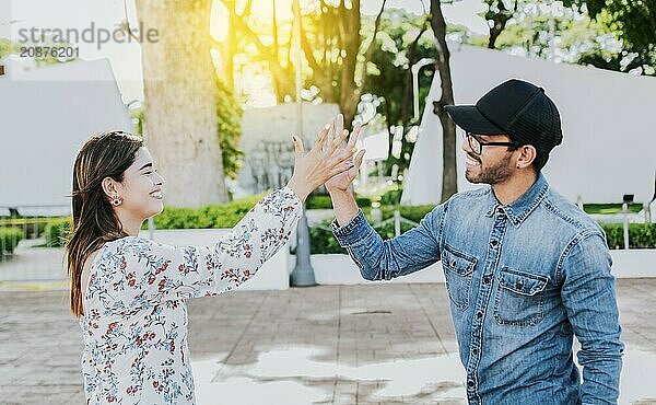 Girl and a guy shaking hands on the street. Two young smiling friends greeting in the street. Concept of man and woman shaking hands on the street