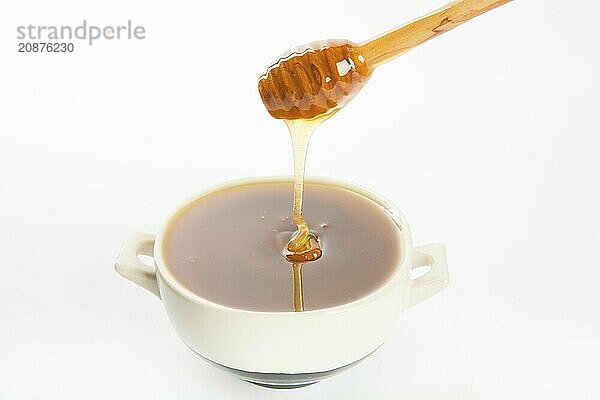 Juicy honey in a cup and spoon on white background