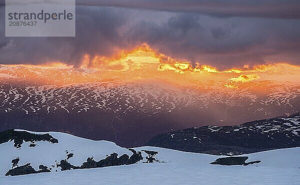 Sunset  clouds in backlight over snow covered mountains  view from top of Fannaråken  Jotunheimen National Park  Norway  Europe