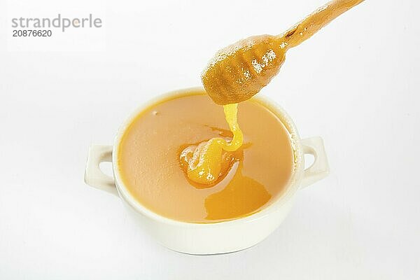 Juicy honey in a cup and spoon on white background