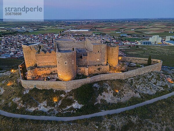 An old castle illuminated at night with a town and wide fields in the background at sunset  aerial view  Consuegra  Toledo  Castilla-La Mancha  Spain  Europe