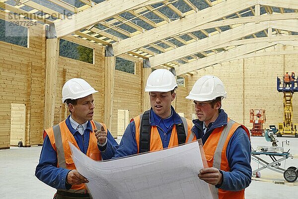 Three builders discuss the plan for a major construction job