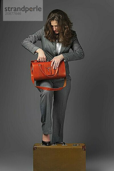 A businesswoman with a bag and a suitcase. On a gray background