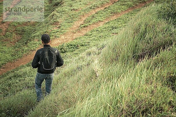 Rear view of male backpacker descending a hill