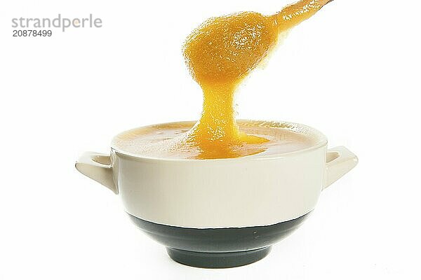 Juicy honey in a cup and spoon on white background