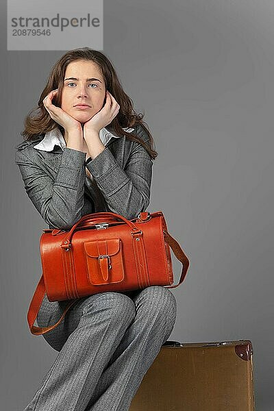 A businesswoman with a bag and a suitcase. On a gray background