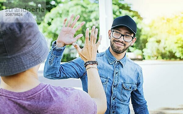 Two smiling friends shaking hands on the street. Friends shaking hands outdoors. Concept of two friends greeting each other with a handshake on the street