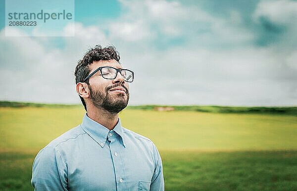 Relaxed young man breathing fresh air in the field. Serene man breathing fresh air in the field