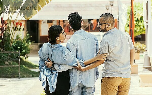 Unfaithful girl walking in the park with her boyfriend while holding another man hand. Woman holding hands with another man while walking with her boyfriend on the street. Love triangle concept