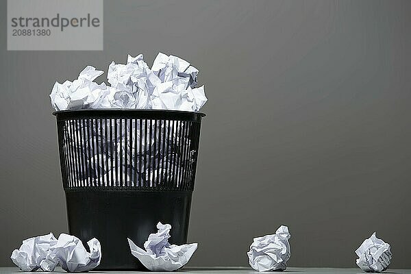 Recycle bin filled with crumpled papers. Gray background