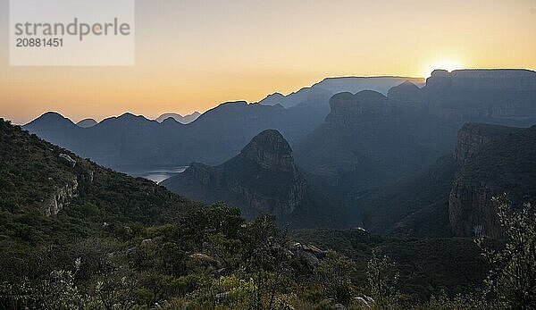 Light mood at sunrise at the Blyde River Canyon  sun rises behind a mountain peak  canyon landscape with sunbeams against the light  view of canyon with Three Rondawels peak and Table Mountains  Panorama Route  Mpumalanga  South Africa  Africa