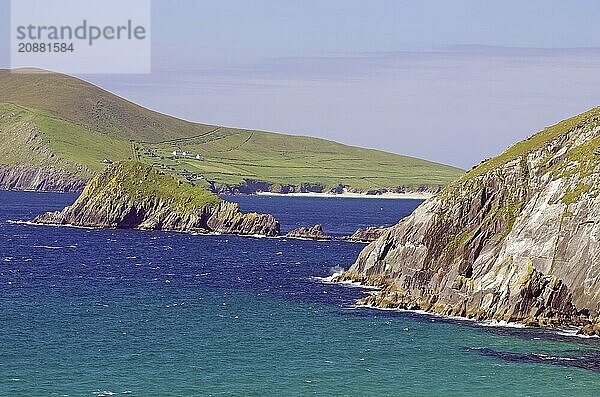 Dramatic coastline with high green cliffs and blue ocean waters under clear skies  Slea Head Drive  Dingle  Ireland  Europe