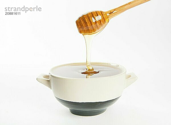 Juicy honey in a cup and spoon on white background