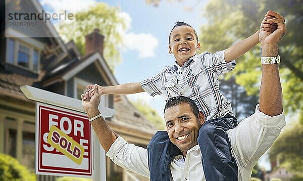 Happy father and son riding piggyback in front of new house and sold for sale real estate sign