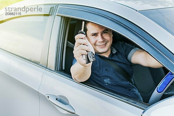 Person in his vehicle showing his car keys  A man in his vehicle showing his new car keys  a happy guy showing the keys of his new car  vehicle rental concept