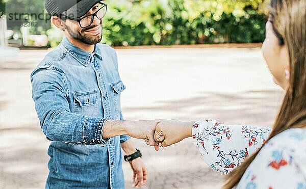 Young man and girl shaking fists in the street. A guy and girl shaking hands on the street. Two young smiling teenagers shaking hands in the street