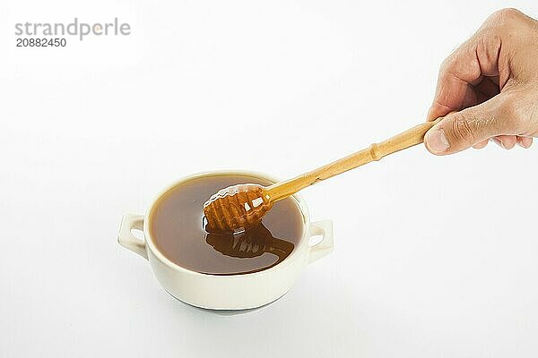 Juicy honey in a cup and spoon on white background