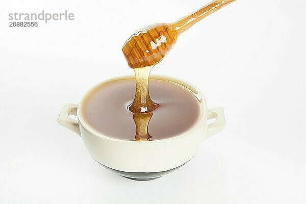 Juicy honey in a cup and spoon on white background