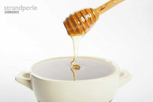 Juicy honey in a cup and spoon on white background