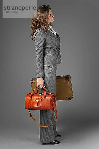 A businesswoman with a bag and a suitcase. On a gray background