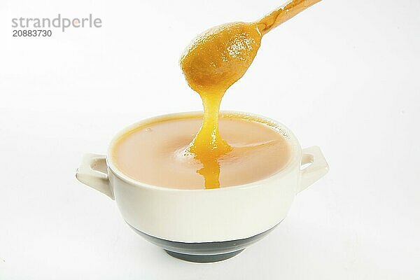 Juicy honey in a cup and spoon on white background