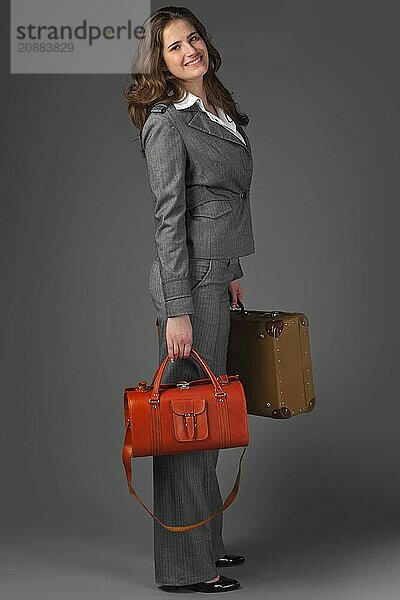 A businesswoman with a bag and a suitcase. On a gray background