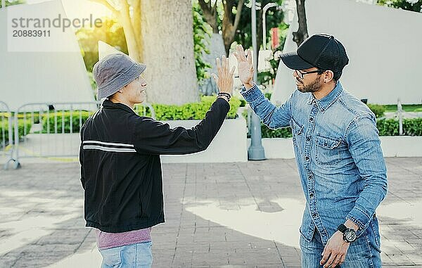 People greeting each other and shaking hands on the street. Two teenage friends shaking hands outdoors