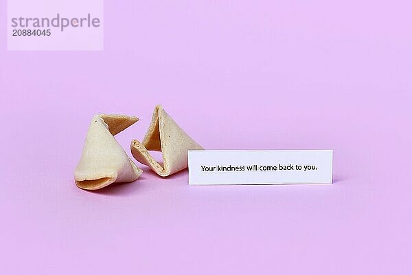 Fortune cookie with motivational text saying Your kindness will come back to you on pink background