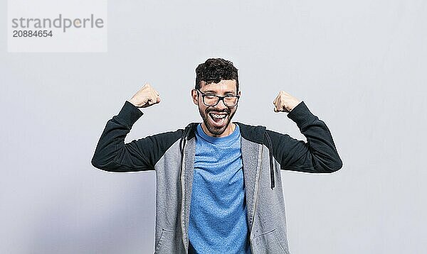 Young man with happy face raising arms in victory gesture isolated. Winner person celebrating victory raising arms isolated