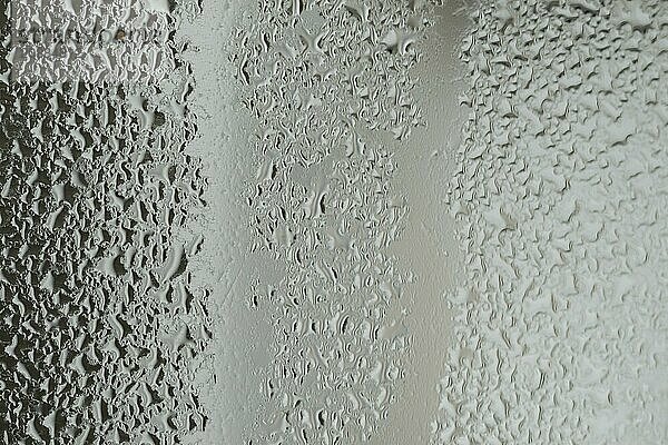 Raindrops on window glass on blur grey background