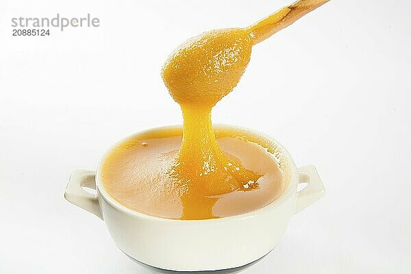 Juicy honey in a cup and spoon on white background