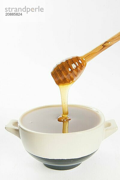 Juicy honey in a cup and spoon on white background