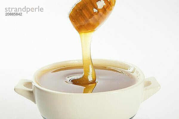 Juicy honey in a cup and spoon on white background