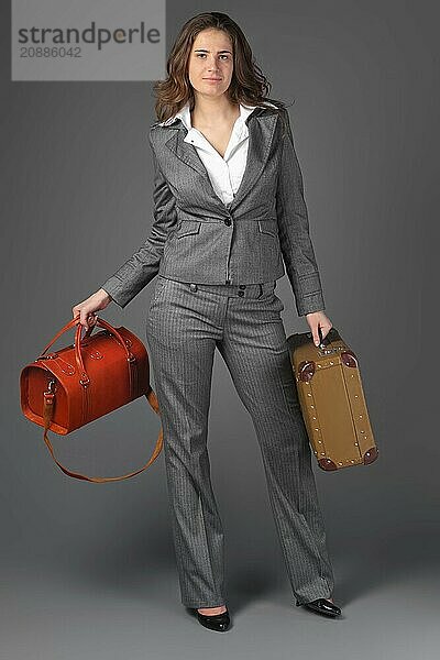 A businesswoman with a bag and a suitcase. On a gray background