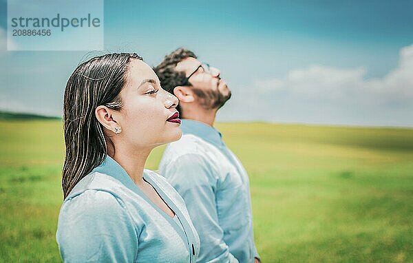 Two relaxed people breathing fresh air in the field. Young couple breathing fresh air in the field