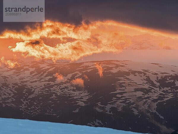 Sunset  clouds in backlight over snow covered mountains  view from top of Fannaråken  Jotunheimen National Park  Norway  Europe