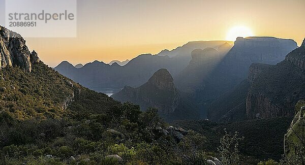 Light mood at sunrise at the Blyde River Canyon  sun rises behind a mountain peak  canyon landscape with sunbeams against the light  view of canyon with Three Rondawels peak and Table Mountains  Panorama Route  Mpumalanga  South Africa  Africa