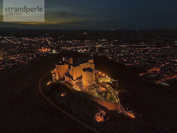 Castle illuminated at night  surrounded by a city and dark surroundings with a tranquil atmosphere  aerial view  Consuegra  Toledo  Castilla-La Mancha  Spain  Europe