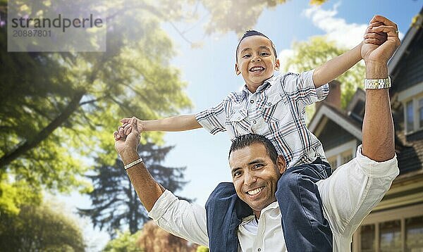 Happy father and son riding piggyback in front yard of their house