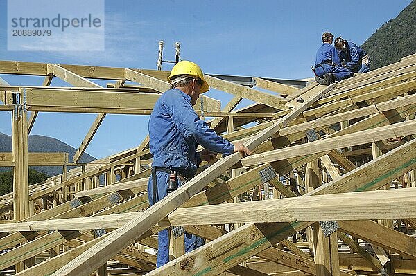 Builders working on the roof of a large house