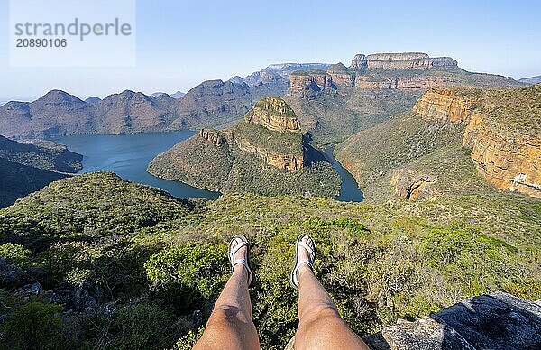 Legs of a sitting woman  view of river bend at Blyde River Canyon with Three Rondawels peak  view of canyon with Blyde River and table mountains in the evening light  canyon landscape  Panorama Route  Mpumalanga  South Africa  Africa