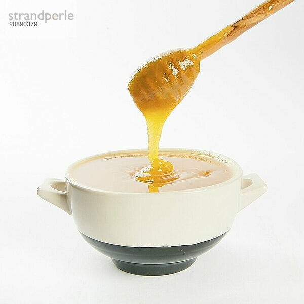 Juicy honey in a cup and spoon on white background