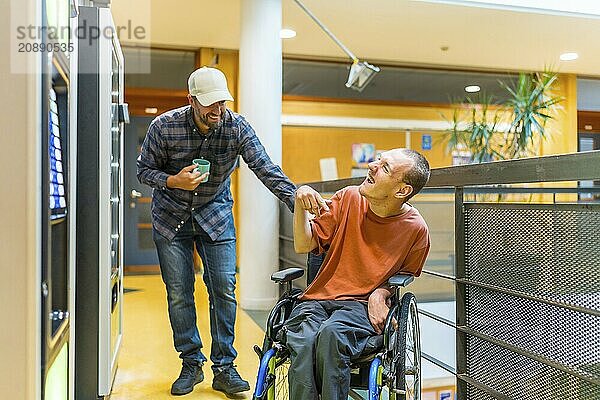 Disabled man and coworker having fun during work break joking next to vending machine in a modern coworking