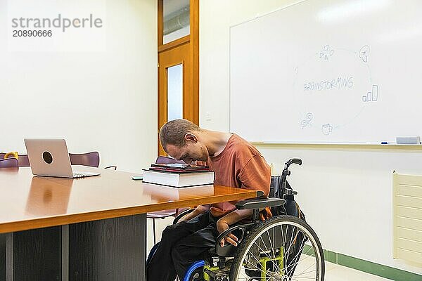 Side view horizontal photo with copy space of a man with cerebral palsy using digital tablet working in coworking