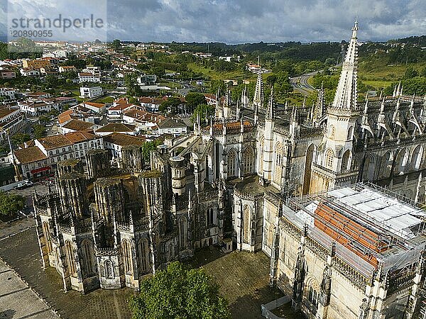 Gothic cathedral with detailed façade in the middle of an urban landscape with houses and green hills  aerial view  monastery  Mosteiro de Santa Maria da Vitória  unfinished chapels  UNESCO World Heritage Site  Batalha  Leiria  Estremadura  Portugal  Europe